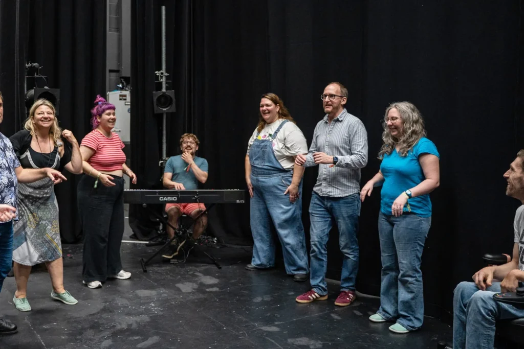 A group of improvisers either side of a musician sitting at a keyboard, in a theatre in Nottingham