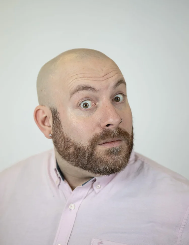 Headshot of improviser Owen Scrivens, looking to the right and wearing a white shirt